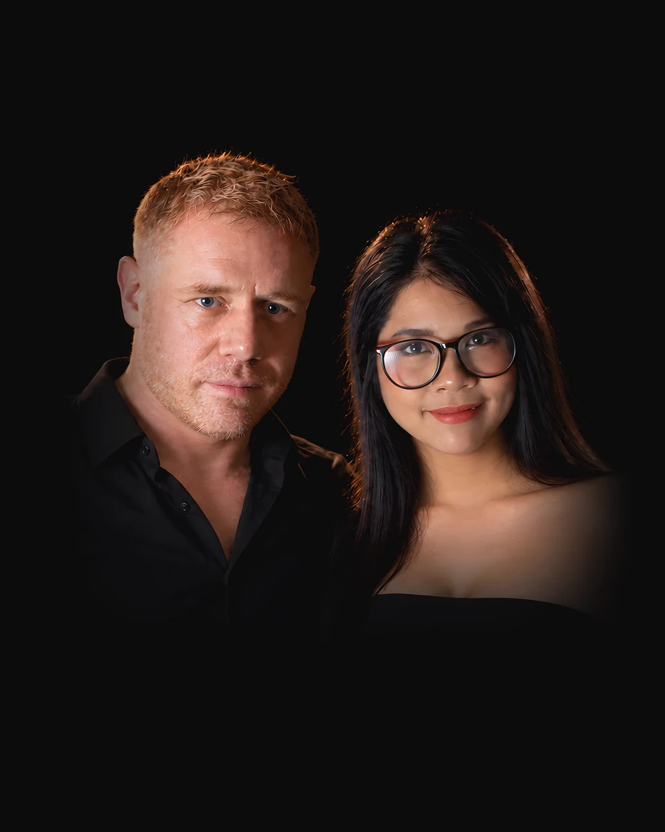 Tim and Paemi, who run Pattaya School Guide, side by side in black.